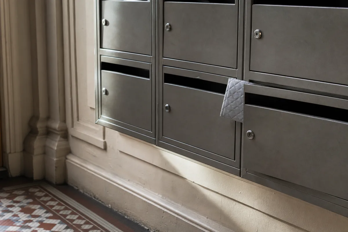 Boîte aux lettres avec petit paquet matelassé, entrée d’immeuble parisien