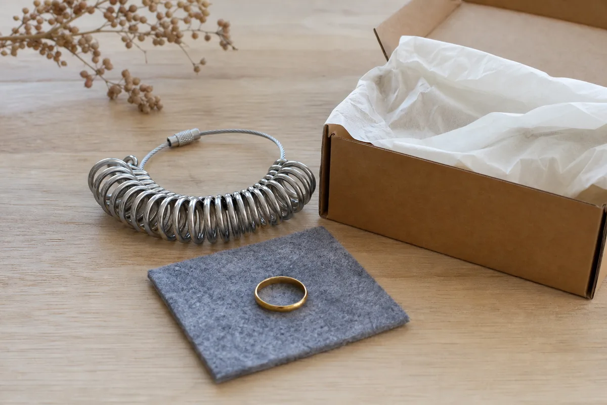 Bague fine et baguier métal posés près d’un carton de retour ouvert